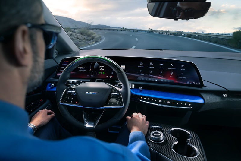 Front View of the 2026 OPTIQ-V Driving Through the Dusk Utilizing its Headlights | Wilson Cadillac of Stillwater in Stillwater OK