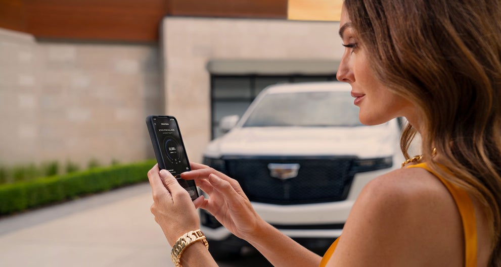 lady checking her mobile with a Cadillac vehicle background | Wilson Cadillac of Stillwater in Stillwater OK
